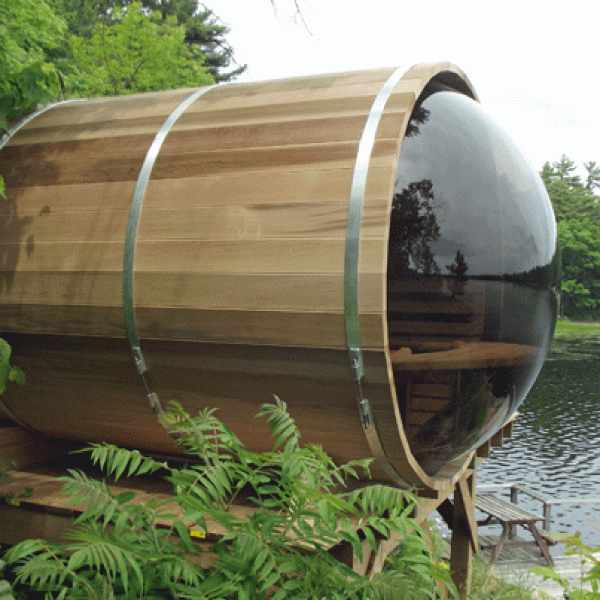 Barrel shaped sauna made from cedar wood, with a dome window overlooking a lake.